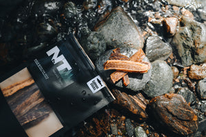 Dehydrated salmon treats for pets coming out of a black bag on the rock by a water stream